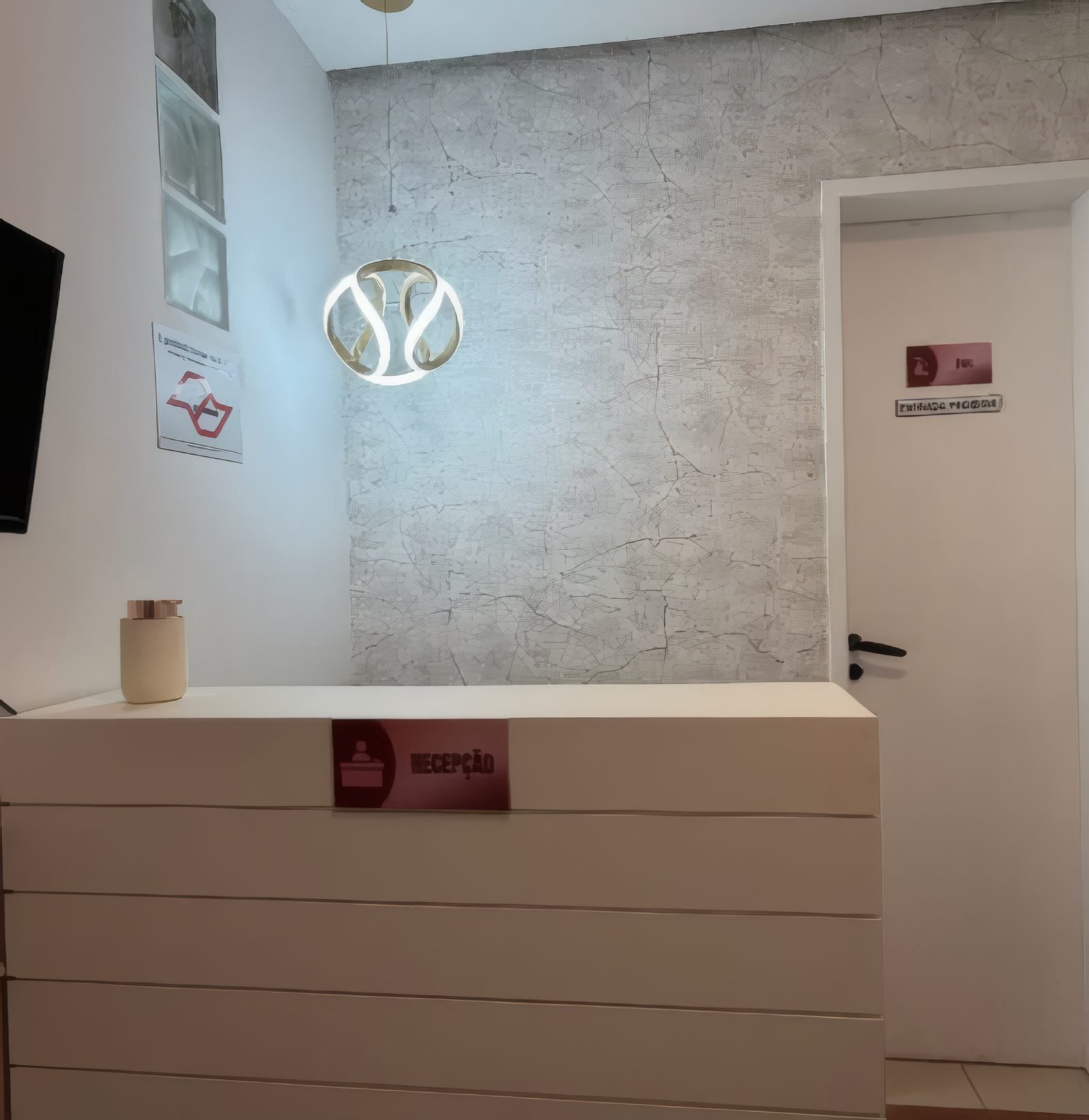 Recepção com balcão branco e luminária dourada